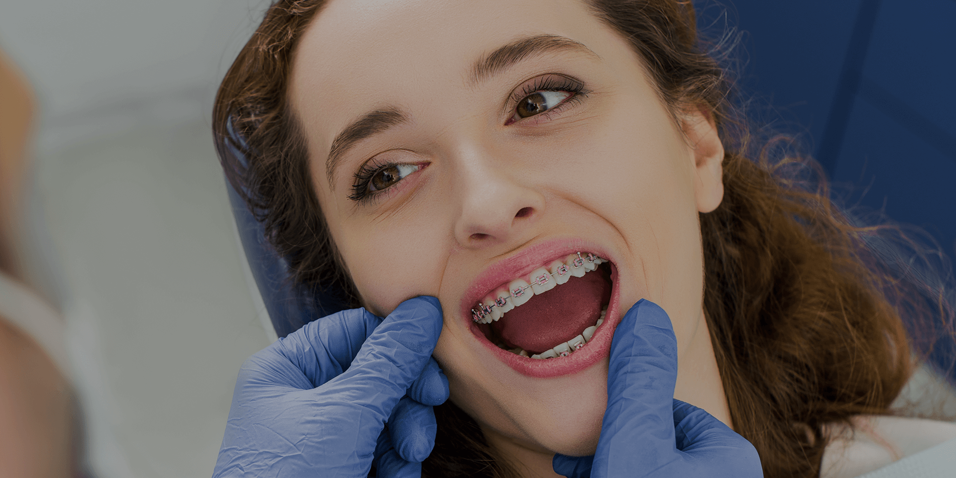 Dentist showing a patient's mouth with braces.