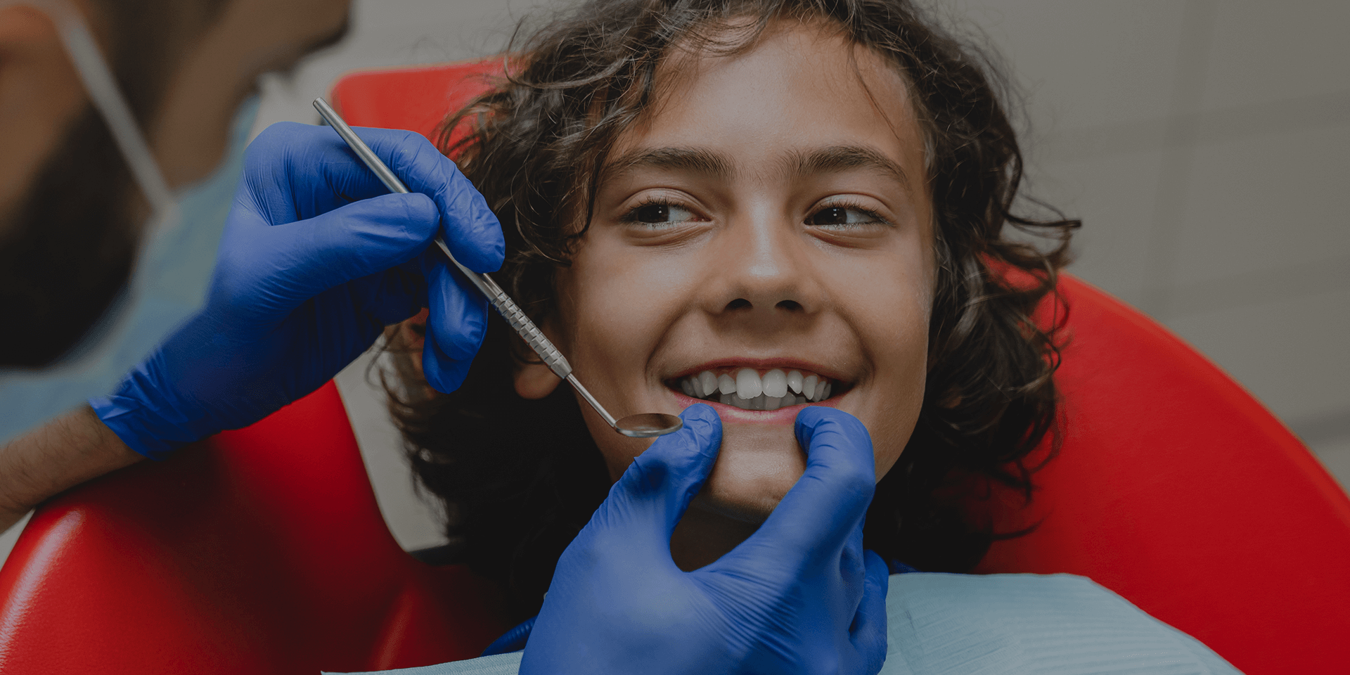 A kid with mouth open being examined by the dentist.